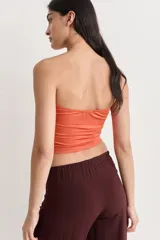 Top strapless color ladrillo con frunce en el frente y detalle de aberturas verticales.