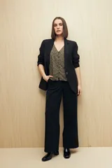 Blusa estampada con motivos de hojas en tonos beige y negro, con escote en V, botones al frente y volados en los hombros.