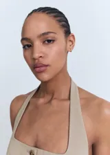Chaleco tipo halter de color tostado, con escote pronunciado, cierre frontal de botones y bolsillos de solapa laterales.