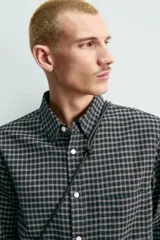 Camisa de corte regular fit confeccionada en una mezcla de lana y algodón. Presenta un diseño de cuadros pequeños, cuello solapa, manga larga con puños abotonados y cierre frontal con botones. Incluye un bolsillo en el pecho.