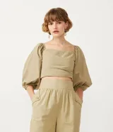 Blusa cropped de tricolina color beige, con escote corazón, detalle cruzado delantero y mangas 3/4 abullonadas. Posee lastex en la espalda para ajuste.