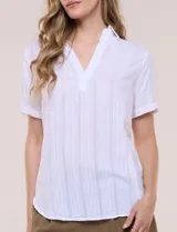 Blusa blanca de algodón texturizado con sutil relieve de rayas verticales al tono, escote en V con cuello solapa pequeño y mangas cortas.