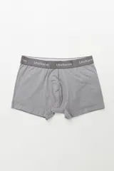Boxer de algodón color gris, con elástico ancho gris oscuro que lleva la inscripción "Uniform" en blanco.