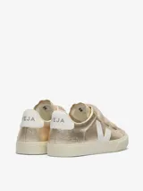 Championes Veja modelo Recife, color dorado metalizado con detalles en blanco. Presentan cierre con tres tiras de velcro y suela de goma en tono crema.