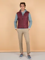 Chaleco acolchado de hombre color gris, con diseño matelasseado horizontal, cuello alto y cierre frontal completo. Presenta un calce ajustado y detalle de logo circular bordado en el pecho.
