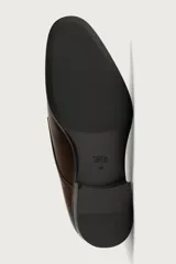 Zapato de vestir tipo monk de color negro, con detalle de doble hebilla metálica plateada en el empeine, puntera redondeada y suela con ligero tacón.