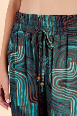 Pantalón palazzo de tiro alto con cintura elástica y cordón ajustable. Presenta un diseño de pierna ancha y fluida con un estampado geométrico de ondas en tonos turquesa y marrón.