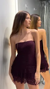 Vestido corto de encaje color bordó, strapless y ajustado al cuerpo, con detalle de volados en el borde inferior.