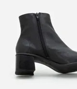 Bota de cuero de caña media para mujer, con punta cuadrada y tacón bloque de 6 cm. Presenta un cierre de cremallera en el lateral interno y una costura central decorativa en la parte frontal.