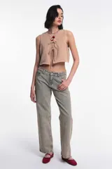 Top corto sin mangas color beige arena, con escote en V y cierre frontal mediante lazos anudados.