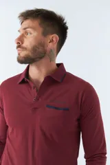 Polo de manga larga negra con cuello clásico, tapeta de dos botones y bolsillo de parche en el pecho con ribete blanco. Logo de la marca bordado en blanco sobre el bolsillo.