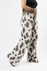 Pantalón wide leg con estampado de vaca en blanco y negro, de tiro alto y cierre de botón y cremallera.