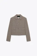 Blazer corto de corte estructurado con cuello solapa, manga larga y hombreras. Presenta cierre frontal con botones metálicos y dos bolsillos delanteros de plastrón con solapa. Diseño con estampado de cuadros tipo príncipe de gales.