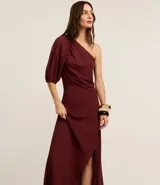 Vestido midi evasê color borgoña, confeccionado en viscolino, con escote asimétrico de un solo hombro, manga corta abullonada y frunces.