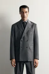 Blazer regular fit de Zara confeccionada en 100% lana, de color gris con diseño de rayas diplomáticas. Presenta cuello con solapas de pico, manga larga con botones en los puños, bolsillos con solapa en la cadera y bolsillo de vivo en el pecho. Cuenta con cierre frontal de botonadura cruzada.
