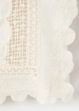 Top blanco de algodón con cuello redondo, detalles bordados, inserciones de encaje y terminaciones festoneadas en mangas y ruedo.