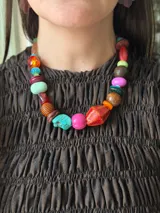 Collar corto de diseño artesanal compuesto por una mezcla de cuentas de diversos materiales, formas y colores vibrantes, incluyendo cerámica, acrílico y piedras. Cuenta con cierre de cadena de acero quirúrgico ajustable.