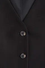 Chaleco negro, corto, con escote en V pronunciado y cierre frontal de tres botones oscuros. Presenta pinzas moldeadoras para un calce entallado y está forrado.