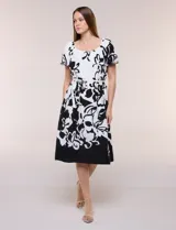 Vestido midi de calce fluido con escote redondo y mangas cortas abullonadas con terminación elástica. Presenta un fino cinturón a tono para ajustar la cintura y una falda evasé con estampa floral abstracta en blanco y negro.