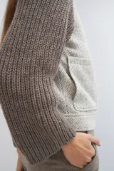 Campera de lana fina color crema, con cuerpo estructurado y mangas de tejido de punto acanalado. Presenta cuello alto, cierre frontal con botones y bolsillos laterales con doble abertura.