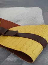 Cinturón de cuero marrón oscuro con una sección ancha en amarillo texturizado, que se ajusta a la cintura.