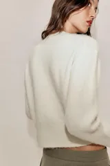 Jersey de punto con mezcla de lana y alpaca, color amarillo mostaza, con cuello en pico y manga larga. Presenta acabados en rib en puños y bajo.
