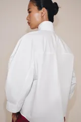 Camisa blanca de algodón de la colección ZW Collection de Zara, con cuello alto, mangas abullonadas por debajo del codo y cierre frontal con botones ocultos por solapa.