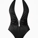 Body halter negro con escote profundo en V, herraje con strass en el centro del busto y diseño fruncido en la cintura. Confeccionado en tela suave y elastizada, tiene espalda descubierta.