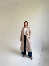 Tapado largo de paño en color beige, con solapas anchas, cierre frontal de un botón y diseño estructurado.