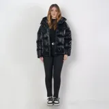 Campera puffer negra de poliéster con interior acolchado, capucha ajustable, cuello alto, cierre frontal con cremallera y botones a presión, dos bolsillos externos con cierre y sistema de ajuste regulable en la parte baja.
