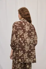 Camisa de silueta amplia y largo por debajo de la cadera, confeccionada en tela liviana con estampado floral en tonos marrón y tostado. Presenta cuello clásico, cierre frontal con botones y mangas tres cuartos.