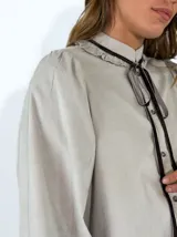 Camisa de pana azul marino con cuello alto, volados en el escote y lazo decorativo. Presenta cierre frontal con botones y mangas largas con puños ajustados.