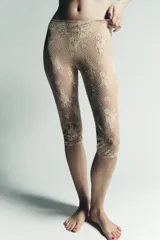Pantalón tipo legging de encaje color dorado/beige, con patrón floral y acabado semitransparente. Presenta cintura y puños elásticos.
