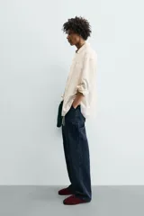 Camisa de corte relajado confeccionada en tejido con mezcla de lino. Presenta cuello solapa, manga larga con puños abotonados, bolsillo plastrón en el pecho y cierre frontal con botones. Incluye bordados a contraste en la espalda.