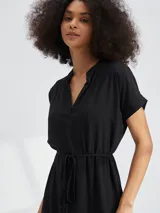 Vestido corto con estampado animal print tipo cebra en tonos blanco y negro. Presenta escote en V, mangas cortas y un lazo ajustable en la cintura para entallar la silueta.