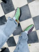 Zapatos chatos color dorado y mostaza con cordones decorativos.