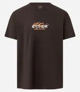 Remera marrón de algodón con cuello redondo y mangas cortas. Estampa en la espalda con diseño de máscara japonesa, serpiente, espadas y flores. Estampa frontal con la frase "Honor and Duty".