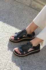 Sandalias negras de cuero con plataforma y tiras anchas.