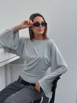 Remera de punto gris melange con cuello bote y mangas largas acampanadas de corte holgado.