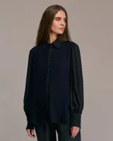 Camisa azul con mangas largas abullonadas, cuello italiano y corte entallado.