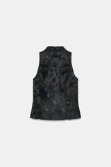 Top negro de tejido jacquard con estampado floral tono sobre tono, cuello redondo y diseño sin mangas. Presenta cierre frontal con alamares y cierre trasero con cremallera oculta.