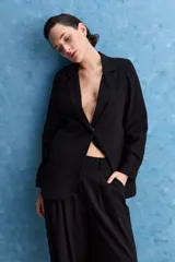 Pantalón negro de tiro alto y calce holgado, con pierna amplia, bolsillos laterales y puños ajustados con botones en los tobillos.