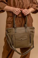 Cartera tipo tote de diseño estructurado en símil cuero, con doble asa rígida y correa regulable. Presenta múltiples bolsillos frontales con cierre y solapa, ofreciendo un estilo versátil y espacioso.