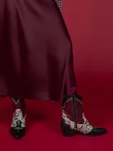 Botas texanas cortas de cuero sintético negro con detalles en animal print y cierre lateral.