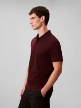 Chomba de manga corta Calvin Klein confeccionada en algodón interlock, con cuello clásico y cierre frontal de botones. Presenta un diseño liso en color bordó con el logo de la marca bordado discretamente en el pecho.