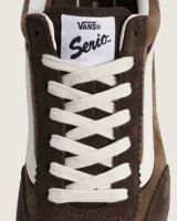 Championes Vans modelo Super Lowpro, de perfil bajo inspiradas en las zapatillas de competición Serio. Confeccionadas en ante y material sintético color marrón, presentan detalles perforados en los laterales, la icónica banda lateral Sidestripe en blanco y suela de caucho con diseño Waffle.