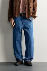 Jeans relaxed fit de mezclilla azul con diseño de bolsillos de carpintero, corte recto y perneras amplias.