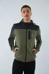 Campera verde militar para hombre con capucha ajustable, cierre frontal completo, bolsillos laterales con cierre y logo estampado en el pecho. Presenta detalles en negro en la parte superior del pecho, hombros y mangas.
