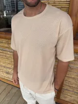 Remera de punto con textura tipo waffle, color beige, de corte holgado y manga corta con cuello redondo.