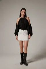 Minifalda de jean blanca con tachas y strass aplicados en la parte delantera, tiro alto y ruedo desmechado.
